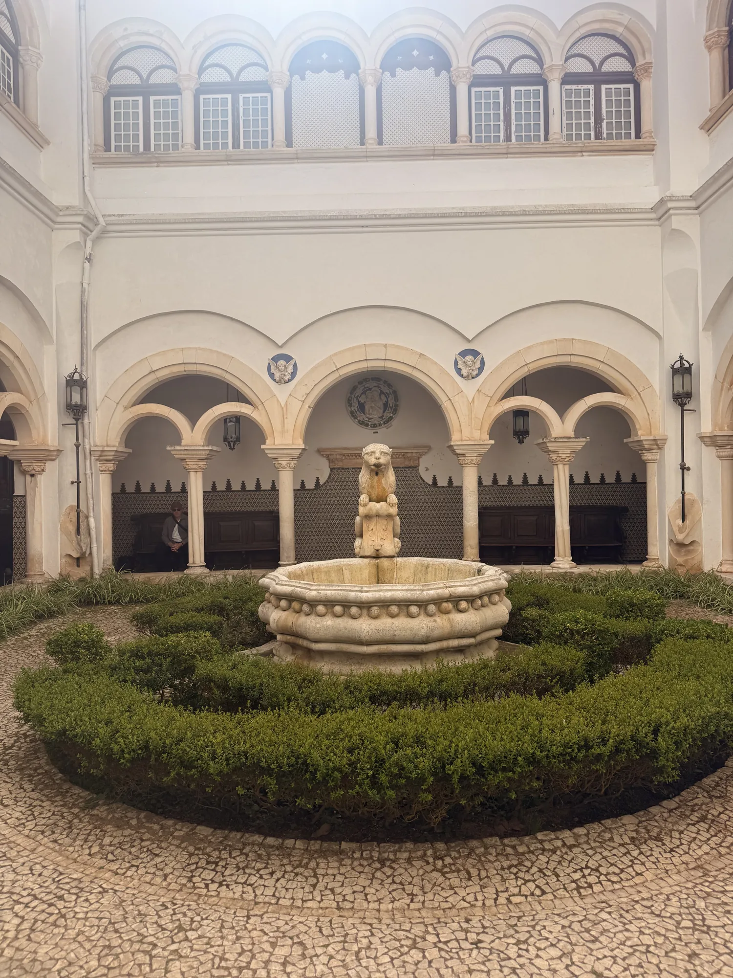 Cascais courtyard fountain surrounded by repeated arches and garden borders