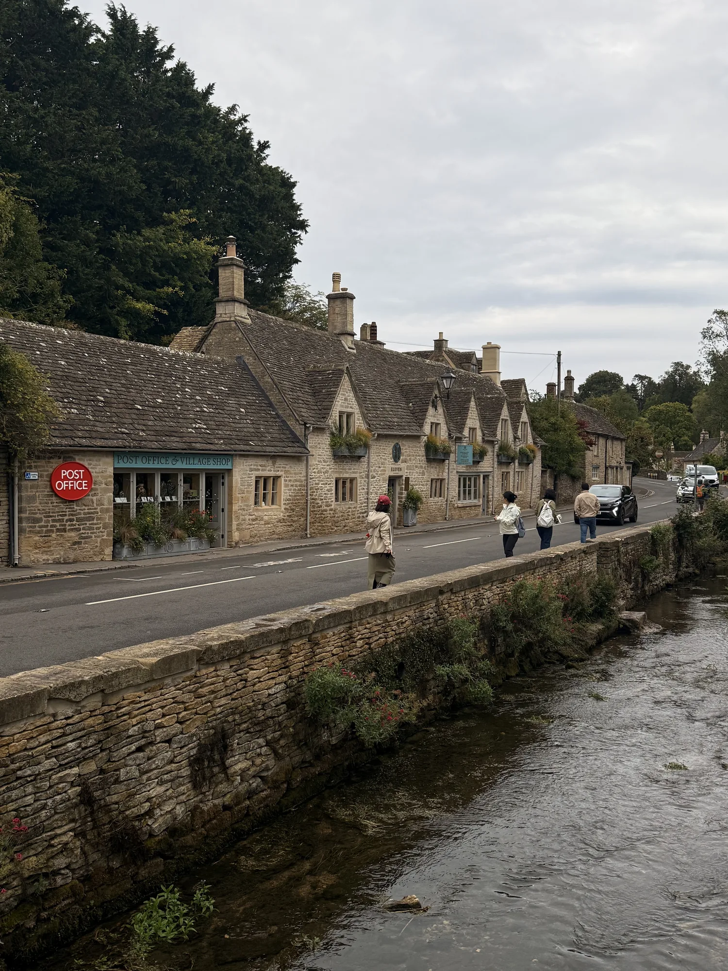 Stone village buildings beside water in the Cotswolds.