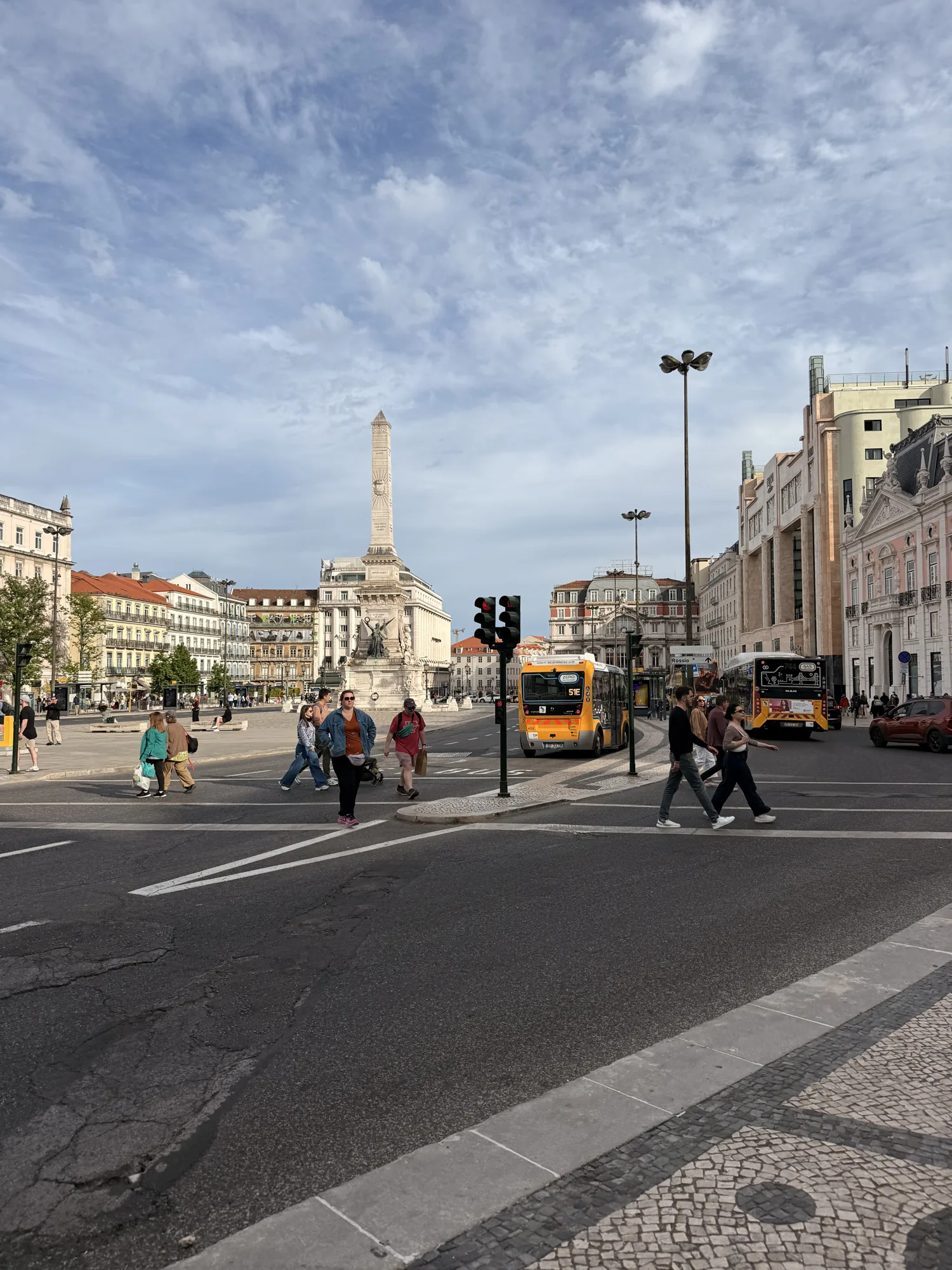 Central Lisbon square with a monument, tram wires and surrounding buildings
