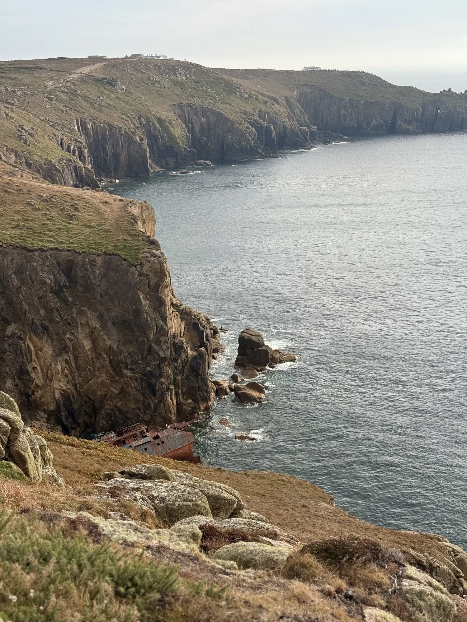 Rocky cliffs and a headland above calm-looking water in west Cornwall.