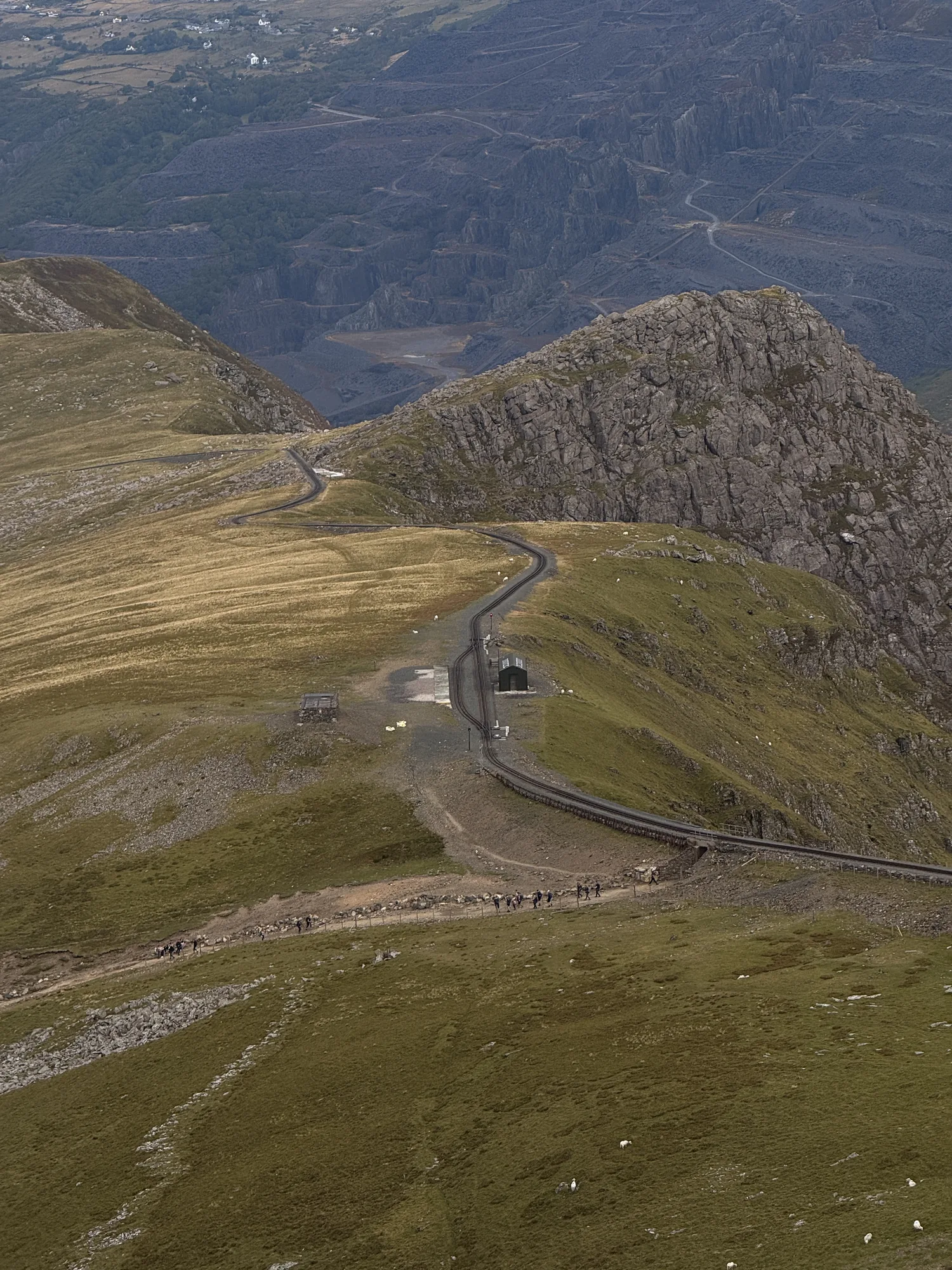 A mountain path and railway below a high ridge in Eryri.