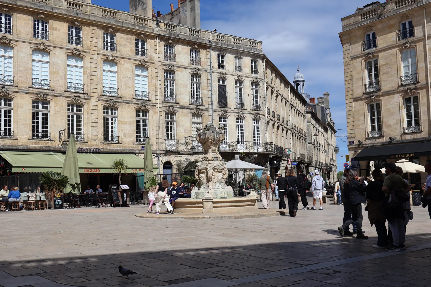 Pale stone buildings and a fountain in a Bordeaux square