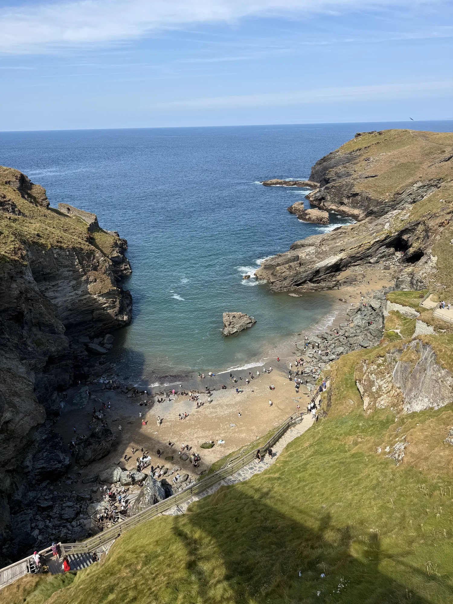 Tintagel’s steep coast, footbridge and pale water close to the shore.