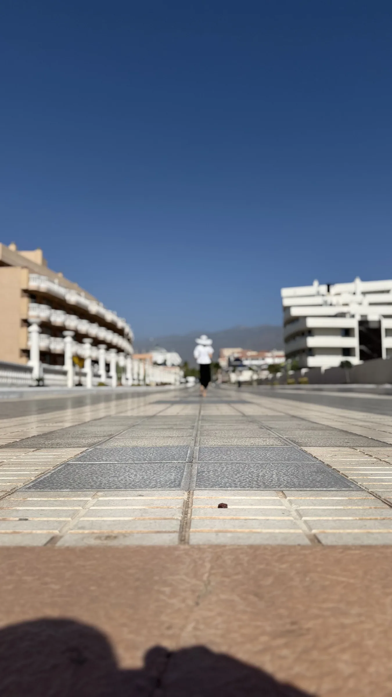 Open paved promenade and resort buildings beneath a clear Tenerife sky