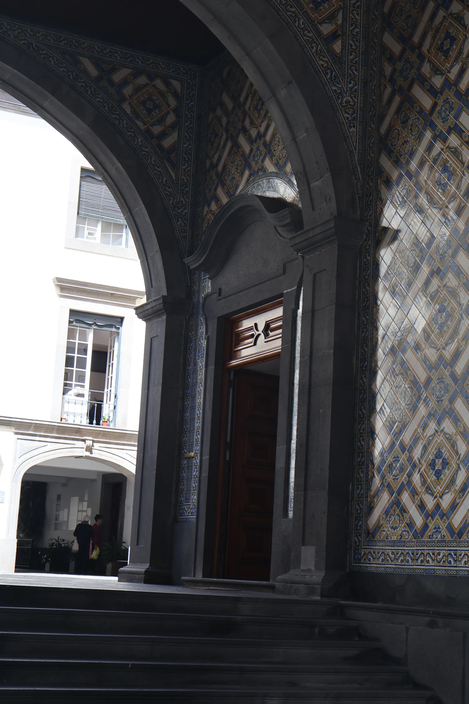 Shadowed stone arcade and wall tiles in Funchal