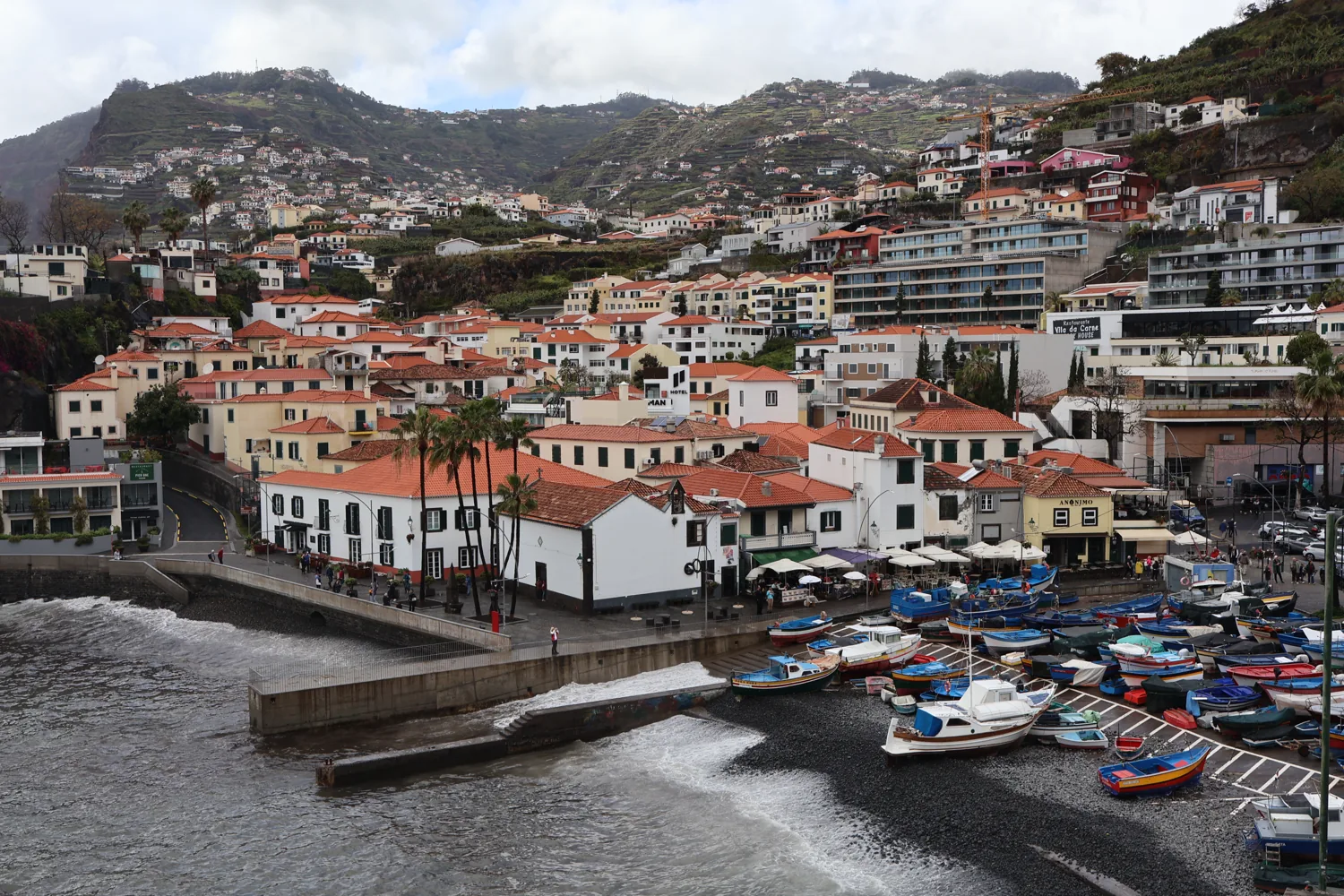 Colourful fishing boats below the hillside houses of Câmara de Lobos
